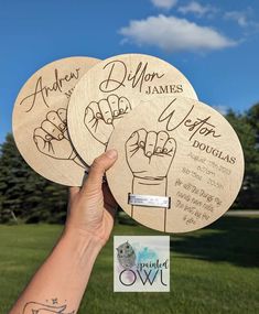 three wooden coasters with handwritten names on them in front of a grassy field