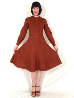 "Vintage 1970's OSCAR de la RENTA Pumpkin Spice Latte Knit Fit and Flare Balloon Sleeve Dress! Features: - balloon sleeves that gather at cuffs with a single button each - fitted bodice with yoke - nipped in waist - flared skirt - 8 matching buttons down front for closure - pumpkin spice latte / orange-brown - no fabric content labels, but feels like a tight knit acrylic Label: \"Oscar de la Renta Boutique\" Bust: up to 36\" Waist: 26\"- 27\" Hips: free Length: 42\" Model is 5' 9\" and measures Retro A-line Vintage Dress For Fall, Vintage A-line Midi Dress For Fall, Retro A-line Midi Dress For Fall, Vintage Brown Midi Dress For Fall, Vintage Long Sleeve Midi Dress For Daywear, Vintage Brown Midi Length Dress, Vintage A-line Midi Dress For Winter, Vintage Brown Knee-length Dress, Vintage Knee-length Midi Dress For Winter