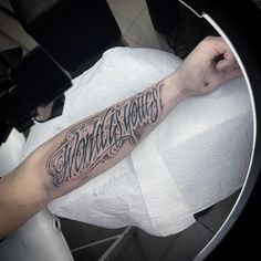 a man with a tattoo on his arm sitting in front of a toilet paper roll