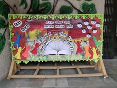 an open book sitting on top of a wooden stand in front of a wall painted with children's pictures