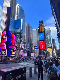 people are standing in the middle of a busy city street with billboards on buildings