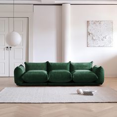 a green couch sitting on top of a wooden floor next to a white rug in a living room