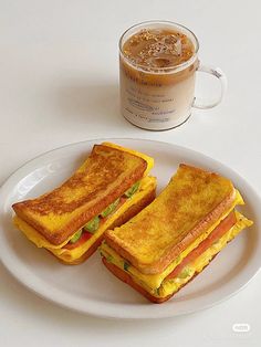 two toasted sandwiches on a plate next to a cup of coffee