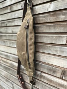 a brown bag hanging on the side of a wooden building with a leather strap around it