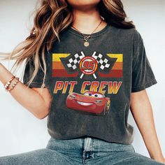 a woman wearing a t - shirt with cars printed on the front and back, sitting down