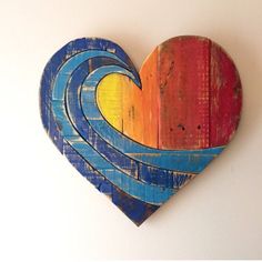 a wooden heart shaped like a wave painted in blue, yellow and red on a white wall