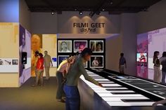 people looking at musical instruments on display in an art gallery, with the words film get written above them