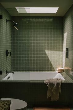 a bath tub sitting next to a toilet in a bathroom under a skylight on the wall