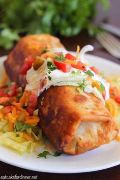 two enchiladas on a white plate with coleslaw and carrots