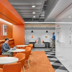 a man is sitting at a table in an orange and white room with checkered flooring