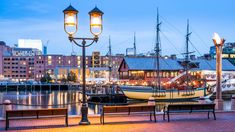 boats are docked in the water at night near some lights and benches with lamps on them