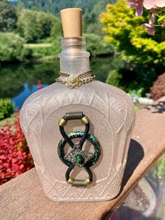 a glass bottle with an odd design on it sitting on a wooden table next to flowers