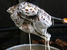 a spoon with some food on it being held by someone's hand over a bowl