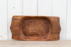 an old wooden tray sitting on top of a table next to a white painted wall