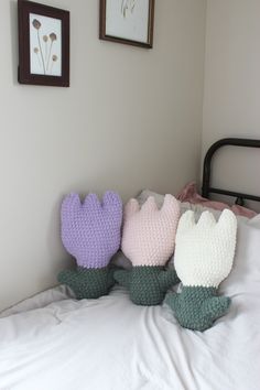 three knitted stuffed animals sitting on top of a bed