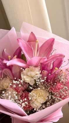 a bouquet of pink and white flowers is wrapped in pink paper with baby's breath