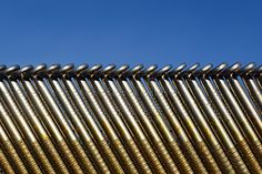 many metal pipes are lined up against the blue sky