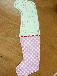 a pink and green stocking with white polka dots on it sitting on a wooden floor