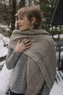 a woman standing in the snow wearing a shawl