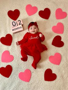 a baby is laying on the floor surrounded by hearts and a sign that says love