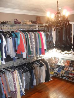 a closet filled with lots of clothes and shoes next to a chandelier hanging from the ceiling