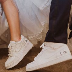 two people standing next to each other wearing white shoes