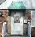 a white door with a green awning next to a brick building