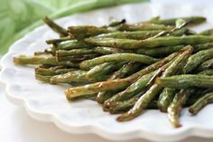 a white plate topped with green beans on top of a table