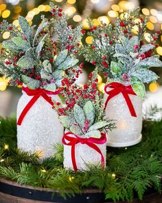 three mason jars decorated with red berries and greenery are sitting on top of a table