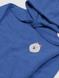 a blue sweatshirt with a white dog embroidered on the front and back side, sitting on a white surface