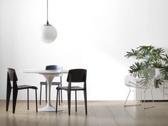 three chairs and a table in a white room with plants on the wall behind them