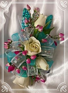 a white rose and blue ribbon corsage on a white satin background with an ornate frame