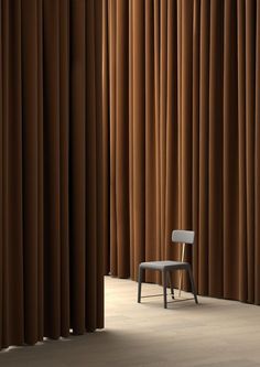 a chair sitting in front of a brown curtain