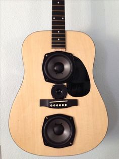 an acoustic guitar hanging on the wall with speakers attached to it's back end