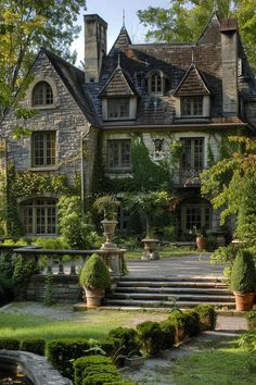 a large stone house with many windows and steps leading to the front door is surrounded by greenery