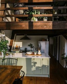 an open kitchen and dining room area with wooden flooring, white counter tops, and stairs leading up to the upper level