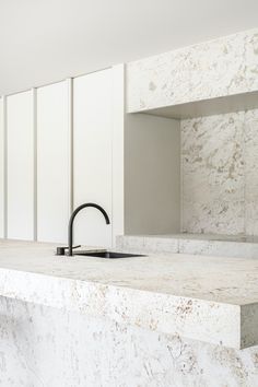 a kitchen counter with a sink and faucet next to white cupboards on the wall