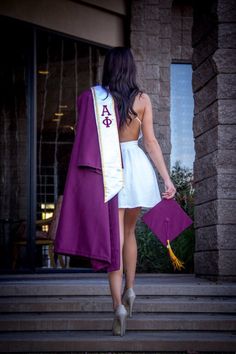 a woman in a graduation gown is walking down the stairs with her purple stole on