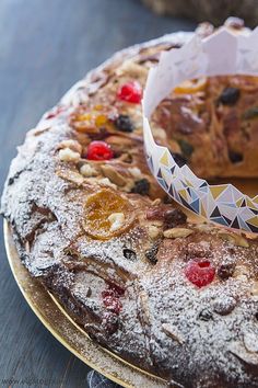 a cake sitting on top of a wooden table covered in powdered sugar and fruit