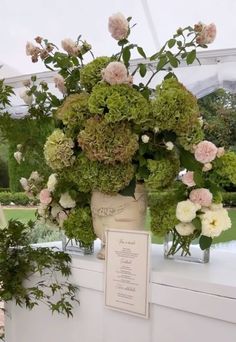 a vase filled with lots of green and pink flowers on top of a white table