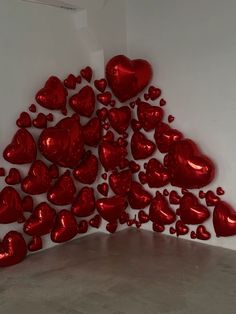 a bunch of red heart balloons are in the shape of a pyramid on a white wall