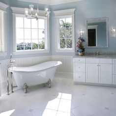 a bathroom with blue walls and white fixtures, including a claw foot tub in the center