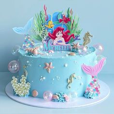 a blue cake with an ariel the mermaid scene on it's top and under water bubbles