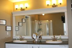 a bathroom with double sinks and mirrors in the wall above it is lit by two lights