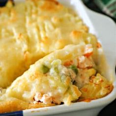 a casserole dish with chicken and cheese in it on a plate next to a fork