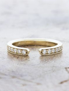 an image of a gold wedding band with diamonds on the top and bottom part, sitting on a marble surface