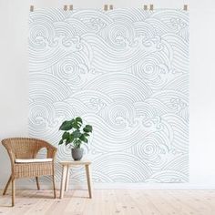 a chair and potted plant in front of a wall with waves painted on it