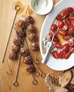 a white plate topped with meatballs covered in toppings and veggie skewers