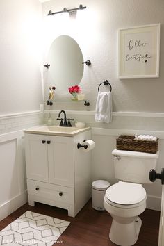 a white toilet sitting next to a sink in a bathroom under a mirror above it