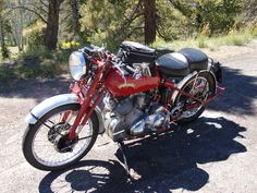 a red and black motorcycle parked on the side of a road next to some trees